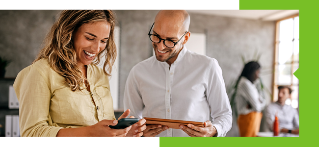 Coworkers review information on a tablet together, engaged in conversation.