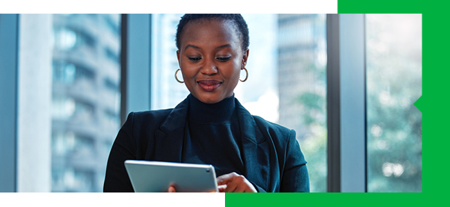 A professional woman confidently engaged in work on a tablet.